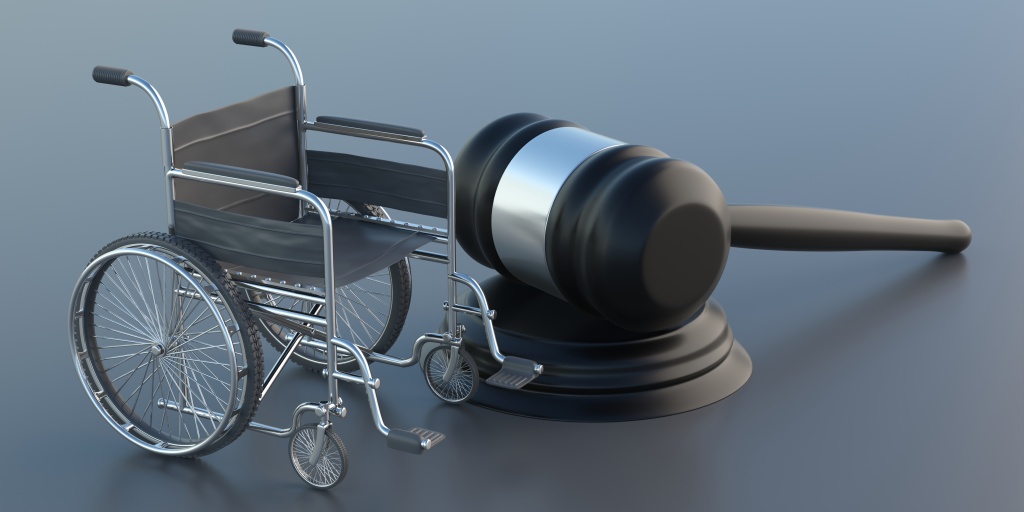 Wheelchair and judge gavel on gray background.